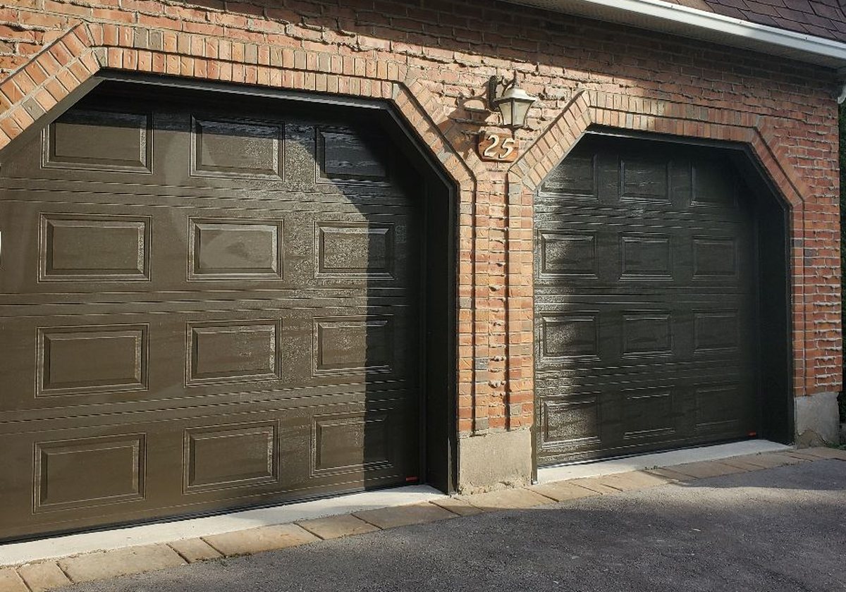 Les deux nouvelles portes de garage brunes installées sur la même maison de brique